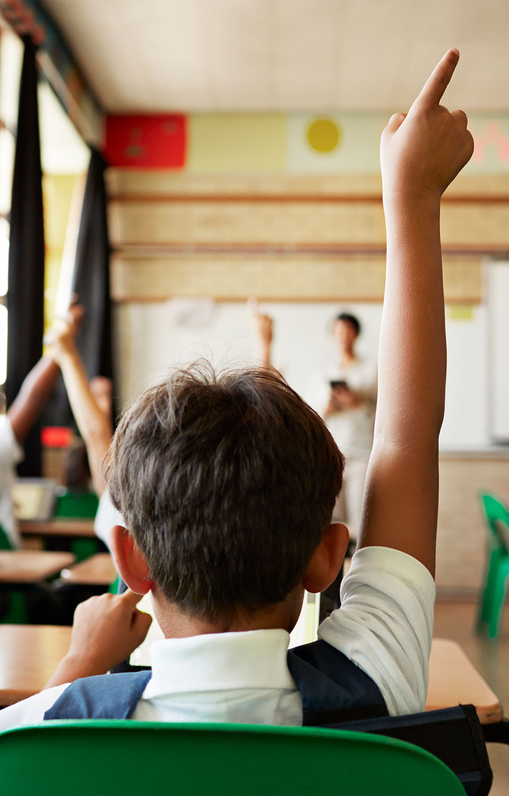 a boy raising his hand in class